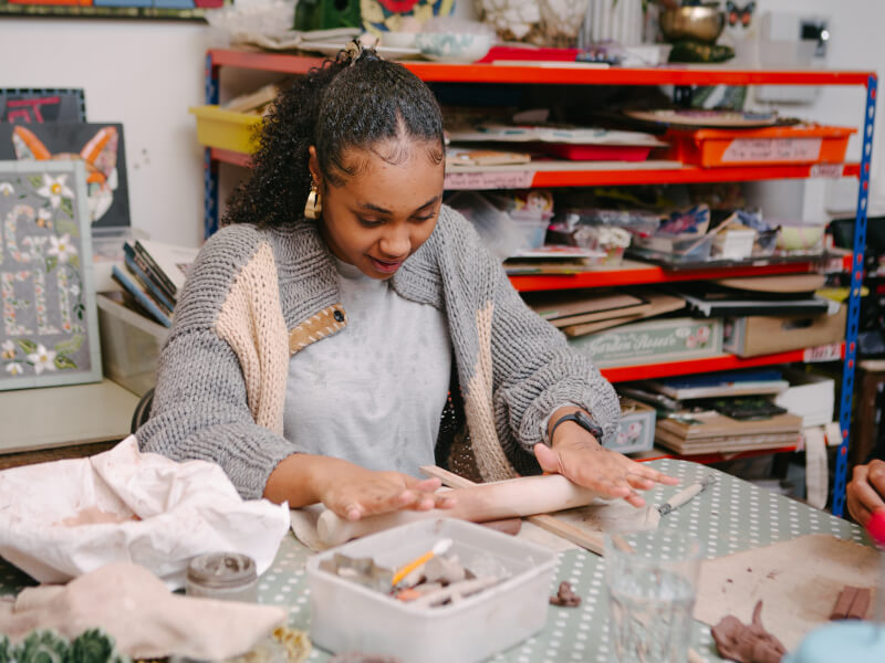 Woman rolling clay in a pottery class